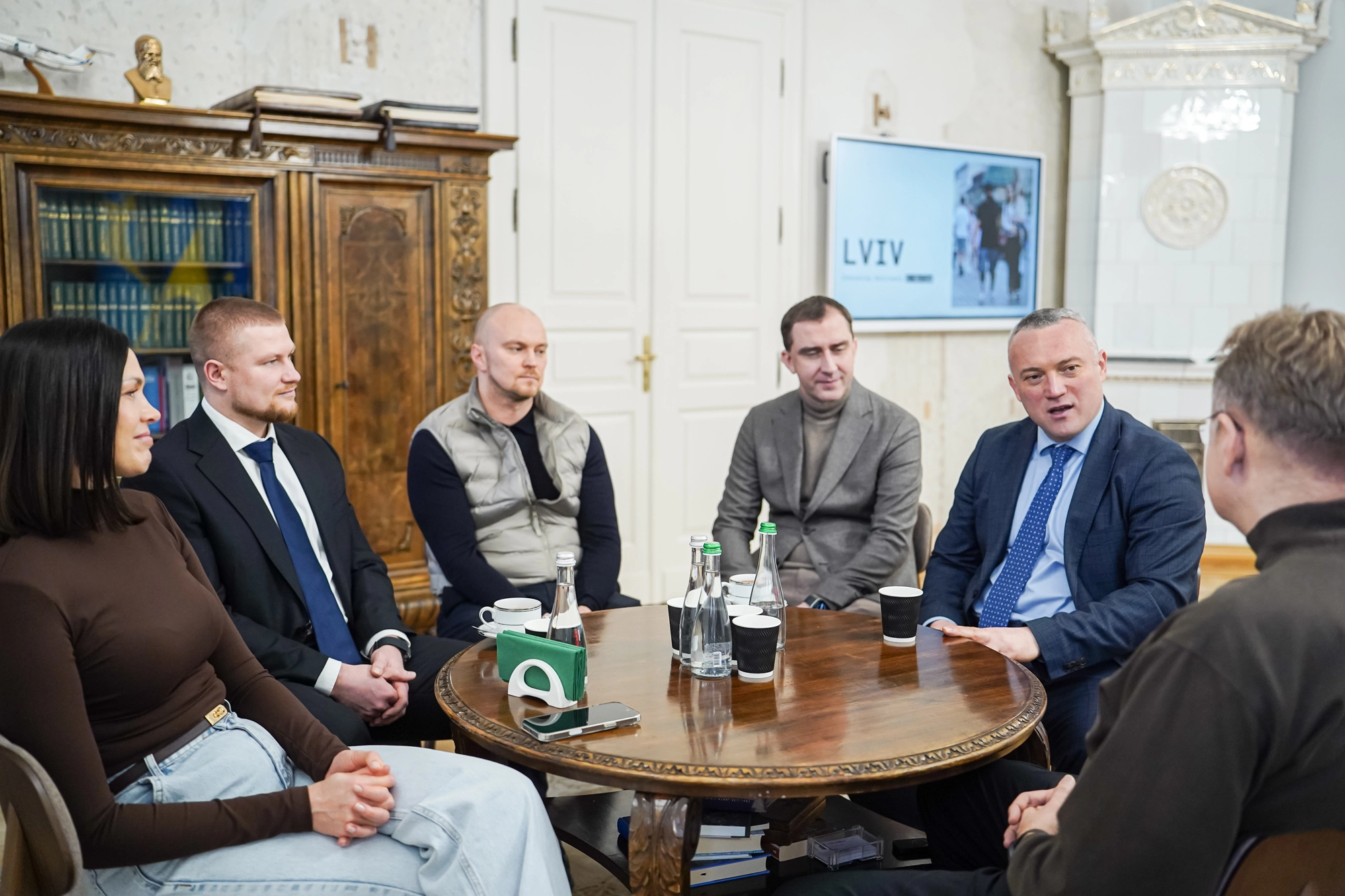 Учасники зустрічі обговорюють розвиток масового спорту у Львові, сидячи за круглим столом у приміщенні