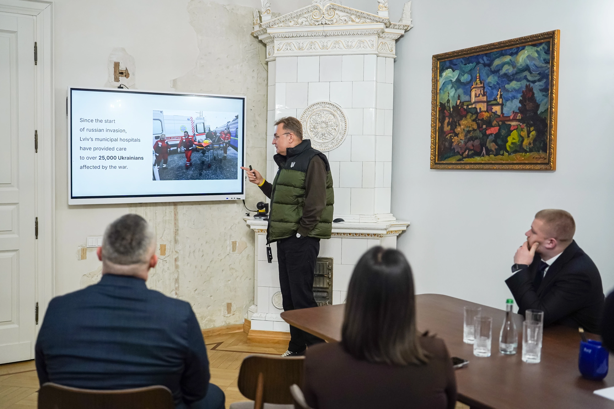 Чоловік у залі презентує на екрані дані про підтримку українців під час війни, присутні слухають