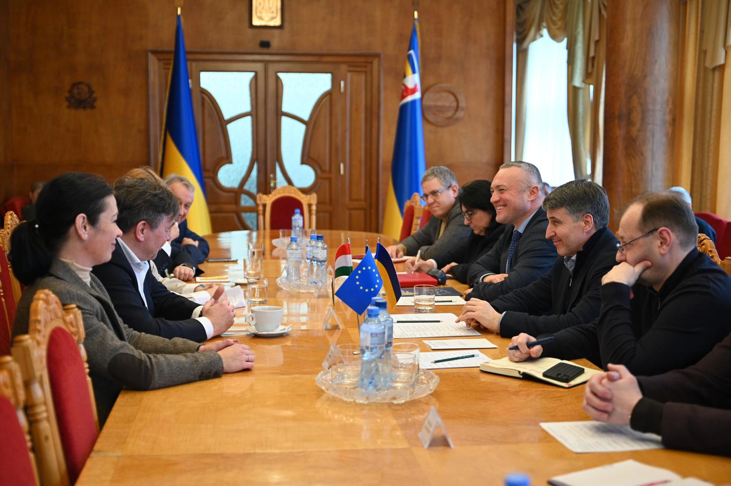 Учасники зустрічі за круглим столом обговорюють розвиток адаптивного спорту, на столі прапори України та ЄС